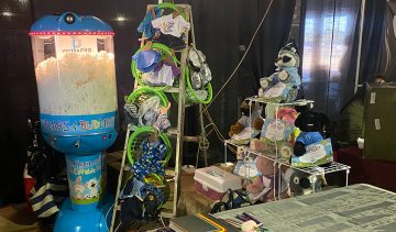 booth display of a machine filled with fluff, baskets of doll clothes, and stuffed animals